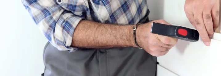 Person bringt Holzverkleidung mit Hammer an